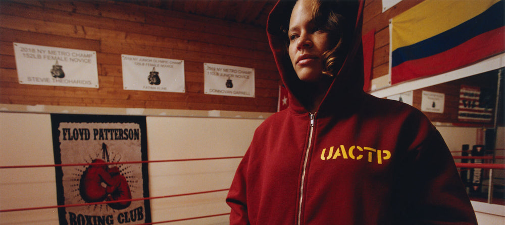 Person wearing a red hoodie with 'UACTP' on it in a boxing club setting.